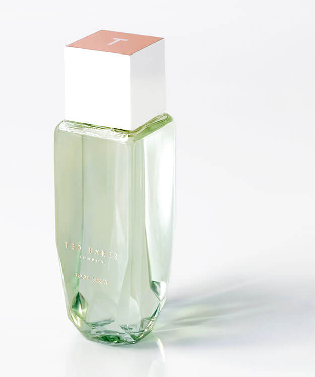 Faceted, gem like Ted Baker body spray bottle, beautifully lit with green liquid inside.