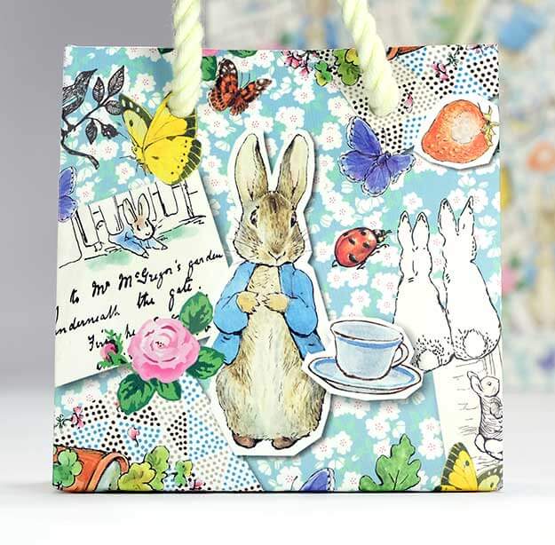 Beatrix Potter Peter Rabbit print design on Paperchase gift bag. Characters and other illustrations on blue background.
